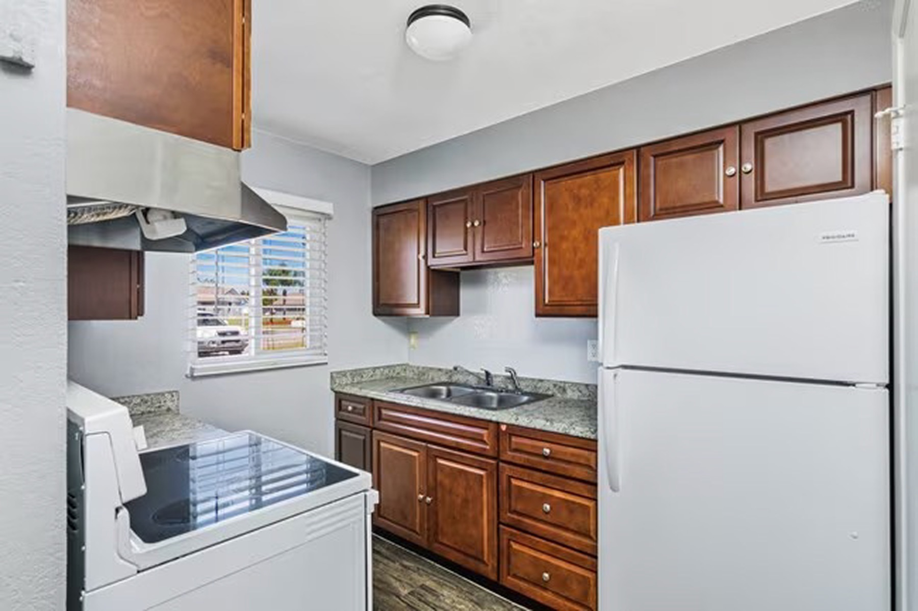 The kitchen of an FNPH rental apartment: a range and hood, wood cabinets, a stone counter and a window onto the parking court.
