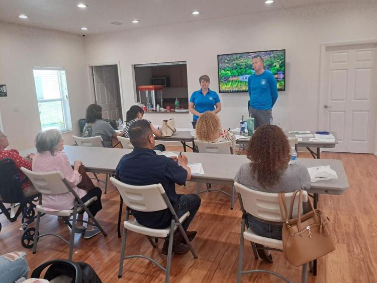 Residents seated at tables in a community room while two FNPH staff members lead a first-time homebuyer workshop.