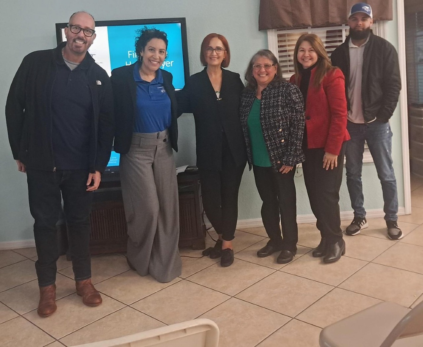 Six FNPH staff members and partner-organization colleagues standing together in a community room after a first-time homebuyer session.