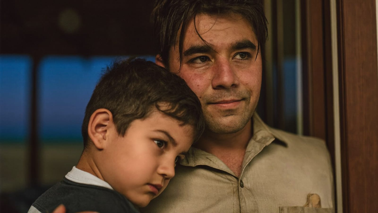 Direction image: a man holds a young boy close in a doorway at dusk, both looking out. Generated illustration, not FNPH photography.